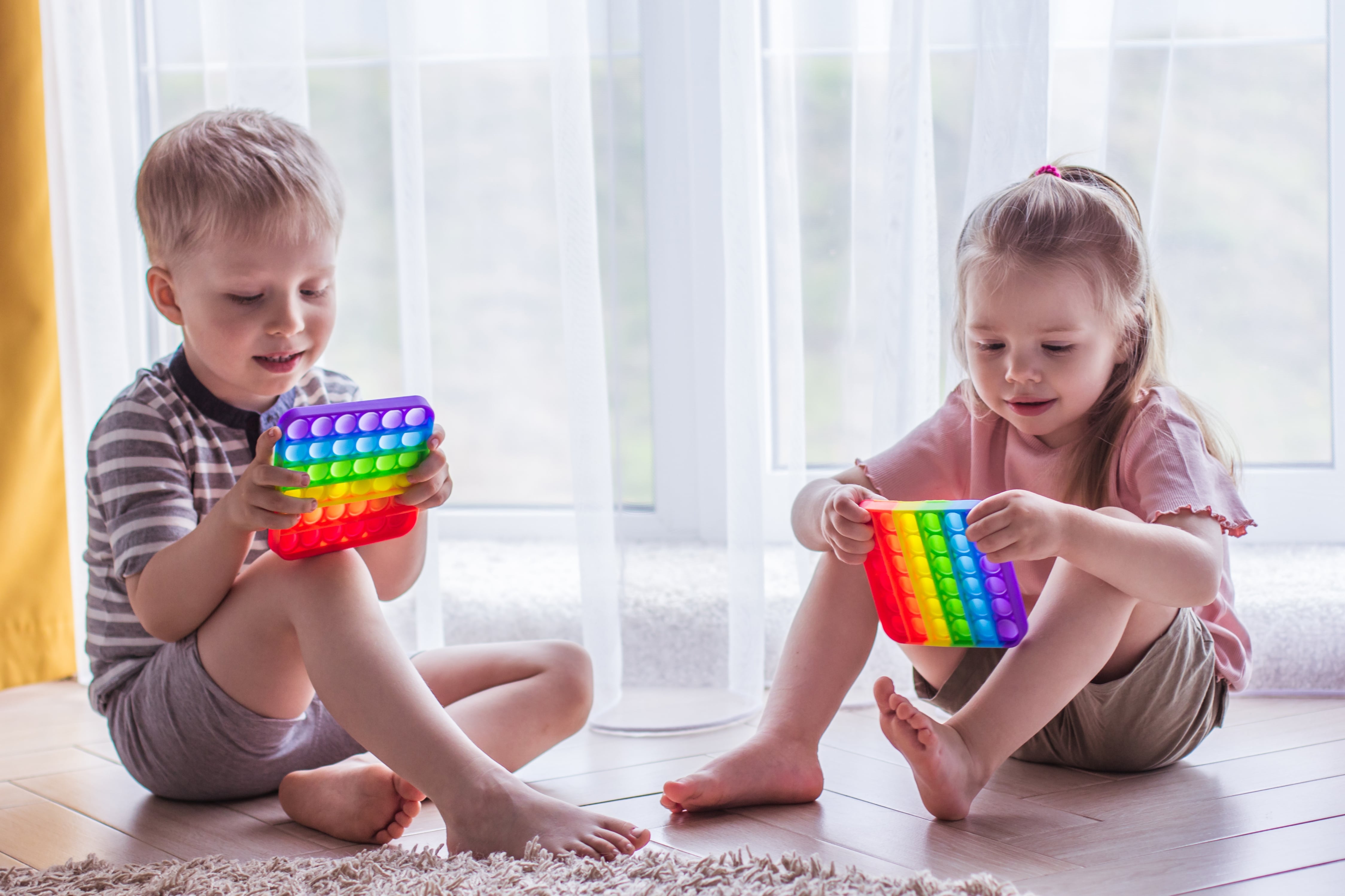 poiss ja tüdruk mängivad Pop It mänguasjaga