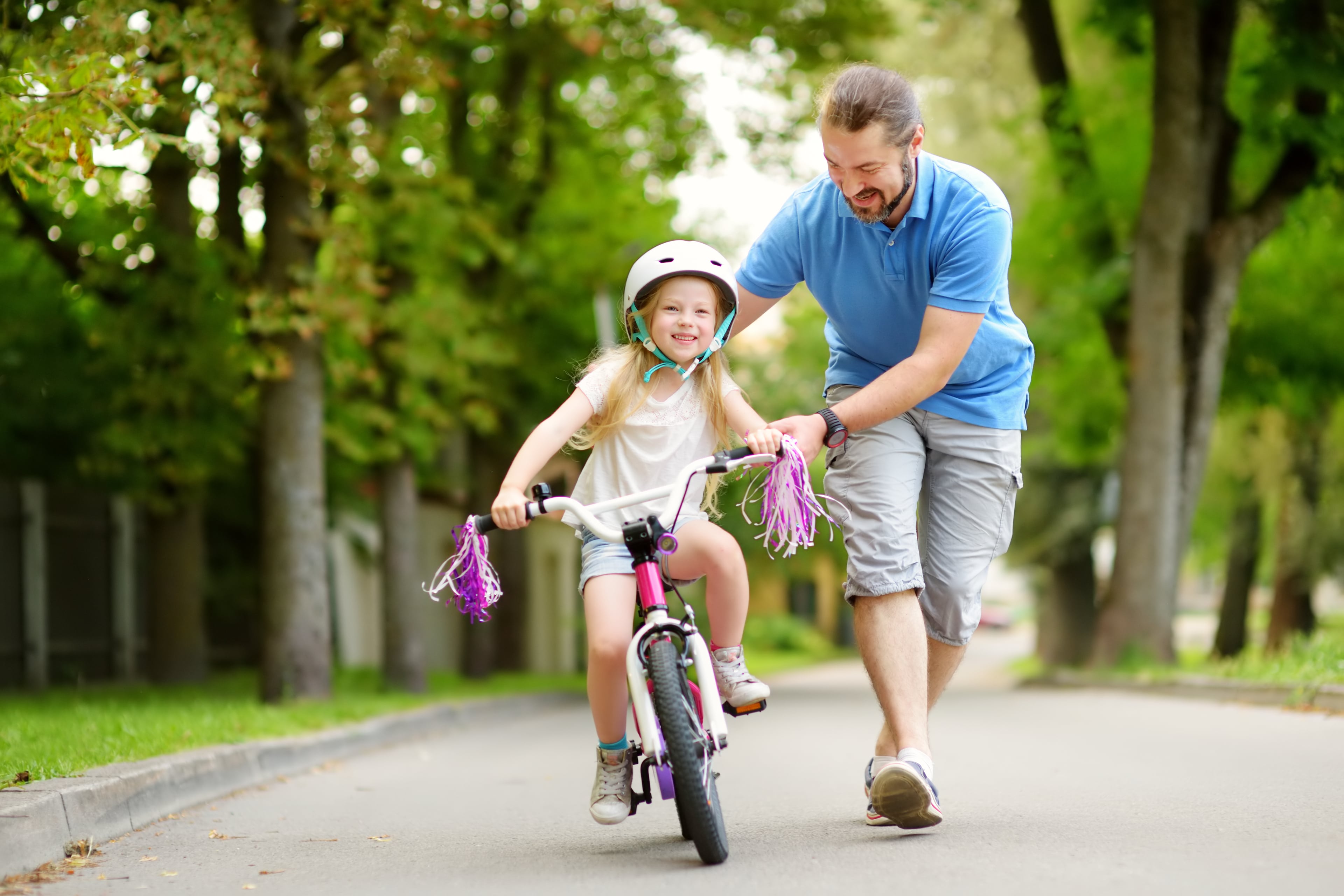 isa õpetab tütart jalgrattaga sõitma